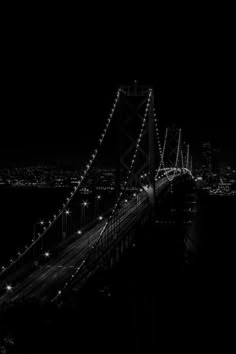 black and white photograph of the bay bridge in san francisco at night with lights on