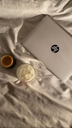 an open laptop computer sitting on top of a bed next to a cup of coffee