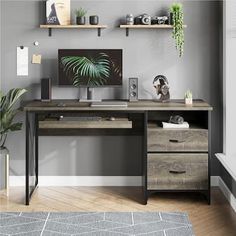 a desk with two drawers and a computer monitor on it, in front of a gray wall