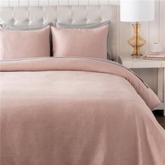 a bed with a pink comforter and pillows