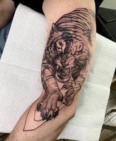 a man's arm with a tiger tattoo on it and a knife in the other hand