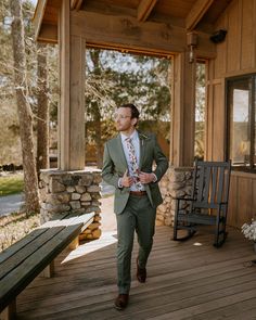 a man in a green suit is walking on a porch with a bench and chair