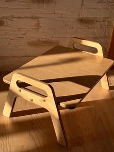 a wooden chair sitting on top of a hard wood floor next to a brick wall