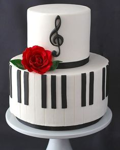 a white cake with piano keys and a red rose