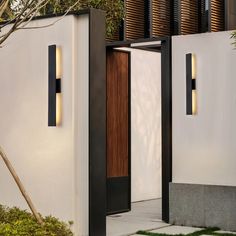 two modern outdoor lighting fixtures on the side of a house