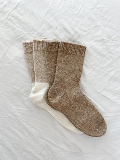 two pairs of socks sitting on top of a white bed sheet covered in wrinkle