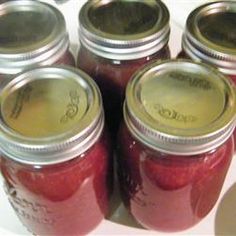 several jars filled with red liquid sitting on top of a white countertop next to each other