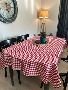 a red and white checkered table cloth with a potted plant on it in front of a clock