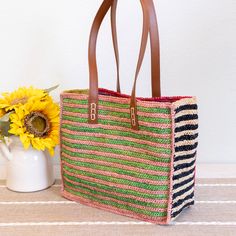 a woven bag sitting on top of a table next to a vase with sunflowers