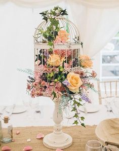 a birdcage filled with flowers sitting on top of a table