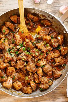 a pan filled with meat and vegetables on top of a wooden table