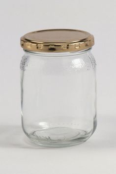 a glass jar with a gold lid sitting on a white surface, it is empty