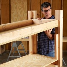 a man standing in front of a wooden shelf with two pieces of plywood on it