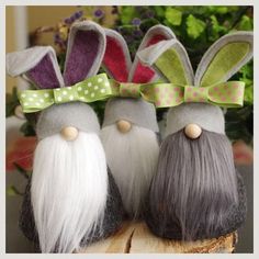 three gnomes with long white hair and green bows on their heads are sitting next to each other