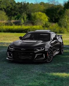 a black chevrolet camaro is parked in the grass