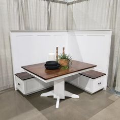 a wooden table with two white drawers underneath it and a vase sitting on top of it