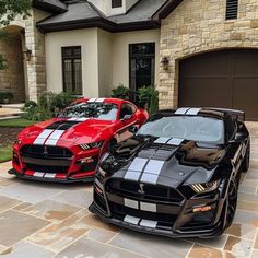 two black and red mustangs parked in front of a house with stone driveway area