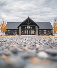 a black and white house sitting on top of a gravel covered field