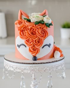 an orange cake decorated with roses and a fox's head is on top of a table