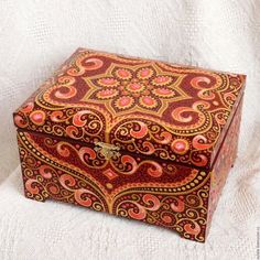 an ornate red and gold box sitting on top of a white cloth