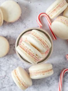 a glass filled with white frosted cookies next to candy canes