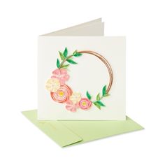 a card with flowers and leaves on the front, sitting on top of a green envelope