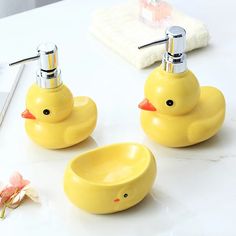 three yellow ducks sitting on top of a white counter next to a flower and mirror