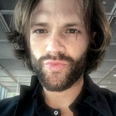 a man with long hair and beard wearing a black shirt