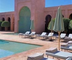 an outdoor pool with lounge chairs and umbrellas