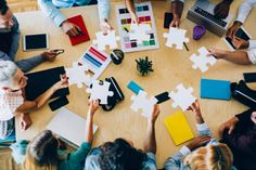 people sitting around a table holding puzzle pieces