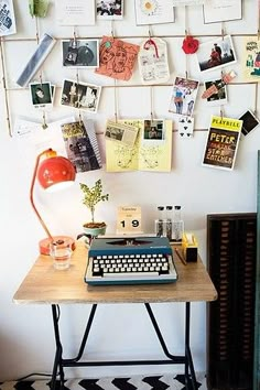 a typewriter sitting on top of a wooden table next to a wall with pictures