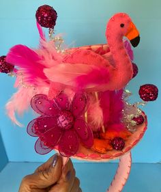 Felt flamingo mini hat headband all hand stitched. Puffy flamingo sets onthe brim of mini top hat adorned with glitterballs and feathers. Hat sits on headband for comfort and support. Perfect for costume and parties.