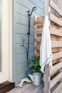 a towel is hanging on the wall next to a potted plant and shower head