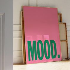 a pink and green poster with the word mood on it in front of a white door