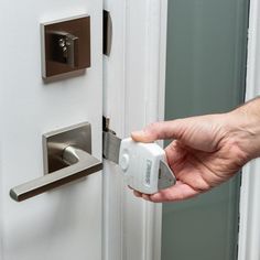 a hand is holding an electronic device in front of a white door with a lock on it