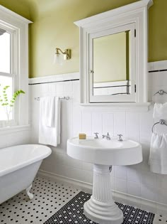 a white bath tub sitting under a bathroom window next to a sink and mirror in a bathroom