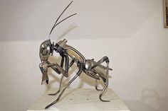 a metal insect sculpture sitting on top of a white table