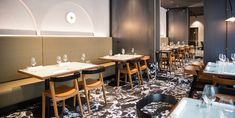 an empty restaurant with tables and chairs lined up against the wall, along with wine glasses on the table