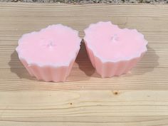 two pink candles sitting on top of a wooden table next to each other with one candle in the middle