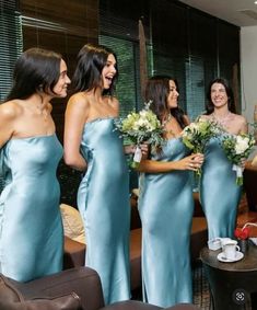 the bridesmaids are laughing together in their blue gowns and holding bouquets