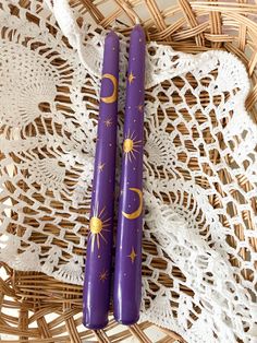 two purple candles sitting on top of a white doily