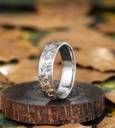 the wedding ring is sitting on top of a piece of tree bark in front of leaves