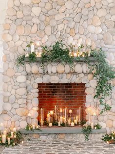 a fireplace with candles and greenery on it