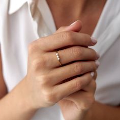 a woman's hand with a diamond ring on her left wrist, wearing a white shirt