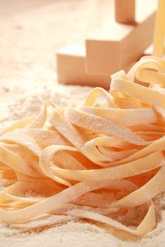 a pile of uncooked pasta sitting on top of a sandy beach next to wooden blocks