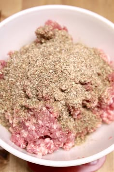 a white bowl filled with ground meat on top of a wooden table