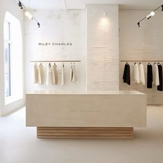 an empty clothing store with white walls and clothes hanging on the racks in front of it