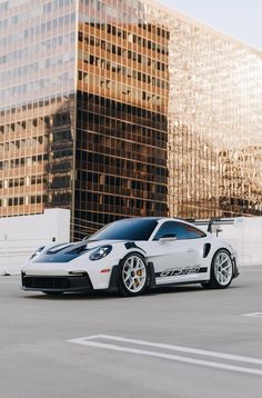 a white sports car parked in front of a tall building