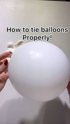 a person holding a white ball in their hand with the words how to tie balloons properly