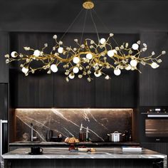 a large chandelier hanging over a kitchen island with marble counter tops and black cabinets